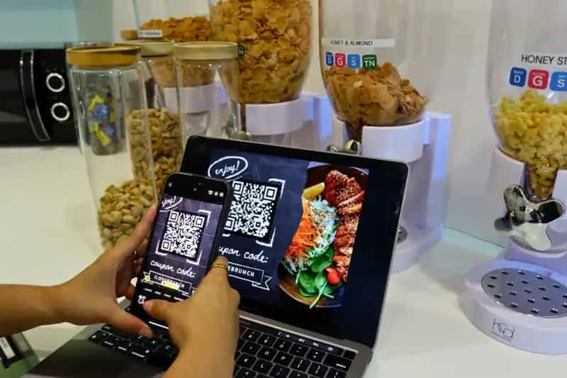 Customer scanning a QR code menu at a restaurant table with a smartphone