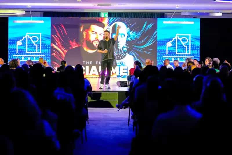 Speaker presenting on stage to an audience at a conference event